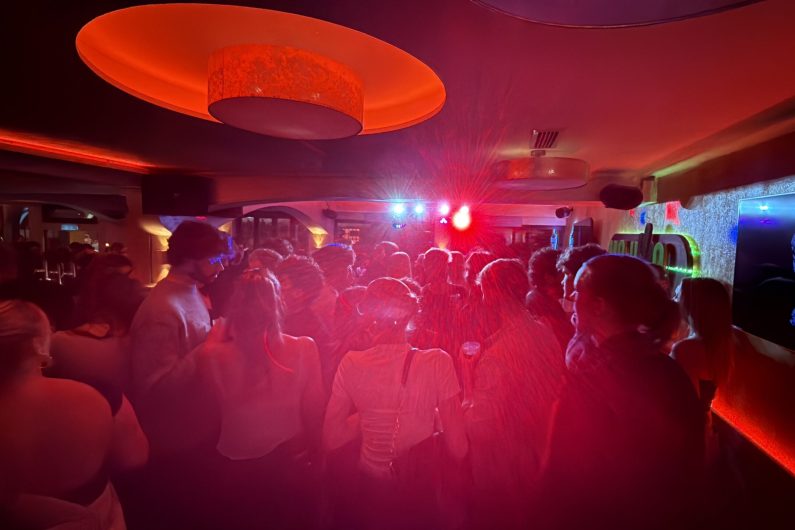 Tanzende Menschen in einer Bar, helles Licht beleuchtet die Tanzfläche