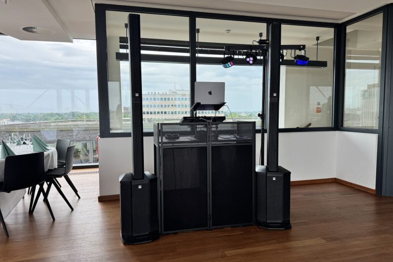 DJ Pult vor einem Fenster, Tontechnik und Lichttechnik sind zu sehen