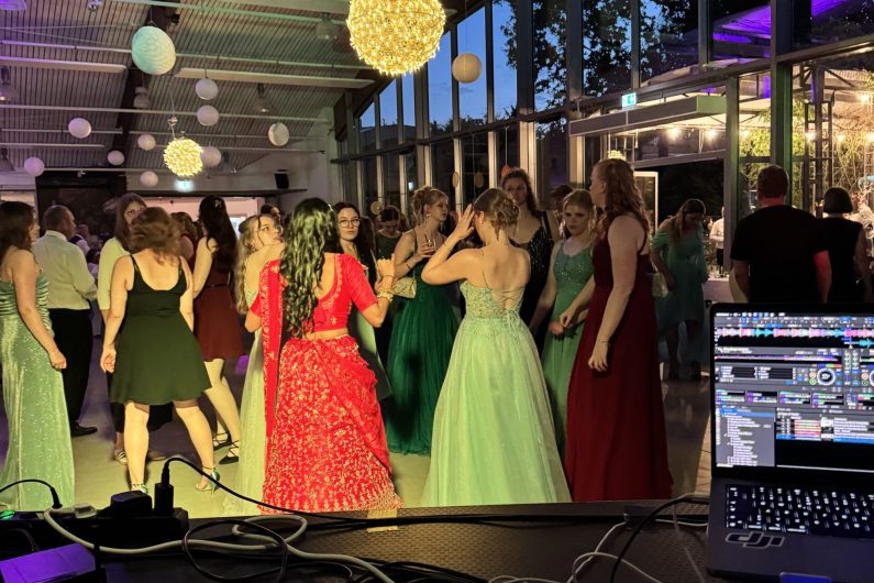 Mädchen in Kleidern tanzen auf einem Abschlussball in der Blumenhalle in Wiesmoor, DJ Pult im Vordergrund